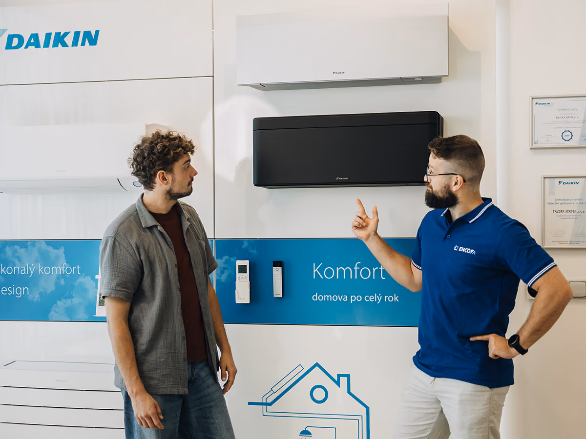 Poradce Encofa ukazuje zákazníkovi nástěnné klimatizace Daikin v showroomu